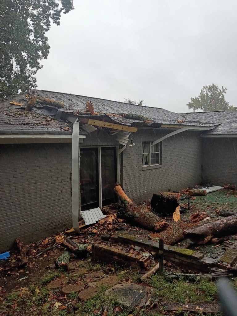 Massive hurricane-downed tree limbs crushed across the brick home’s roof overhang and patio.